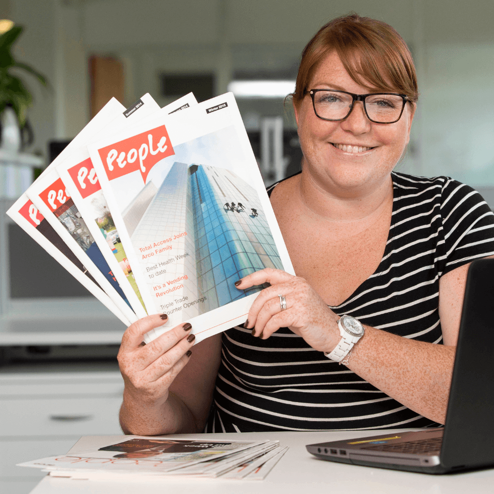 An Arco employee holds up copies of People, the company in-house magazine.
